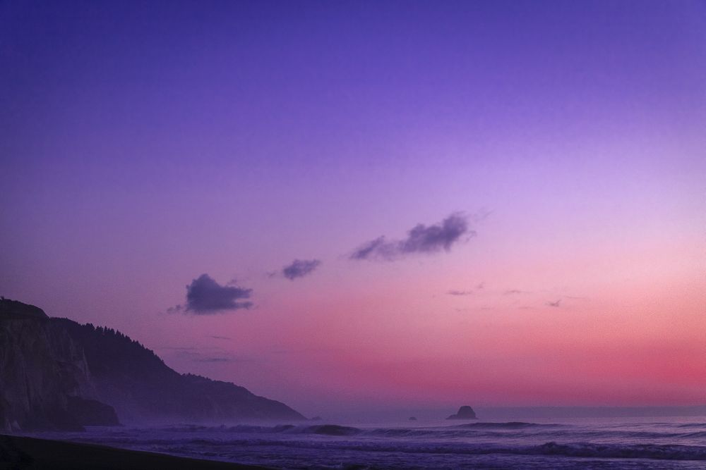 Cliffs over ocean during pink purple gradient sunset
