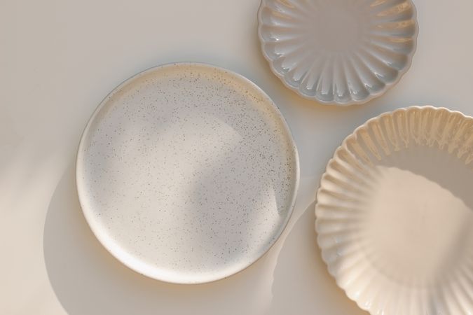 Three neutral ceramic plates on table with shadows