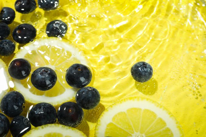Top view of blueberries and lemons soaking in water with copy space