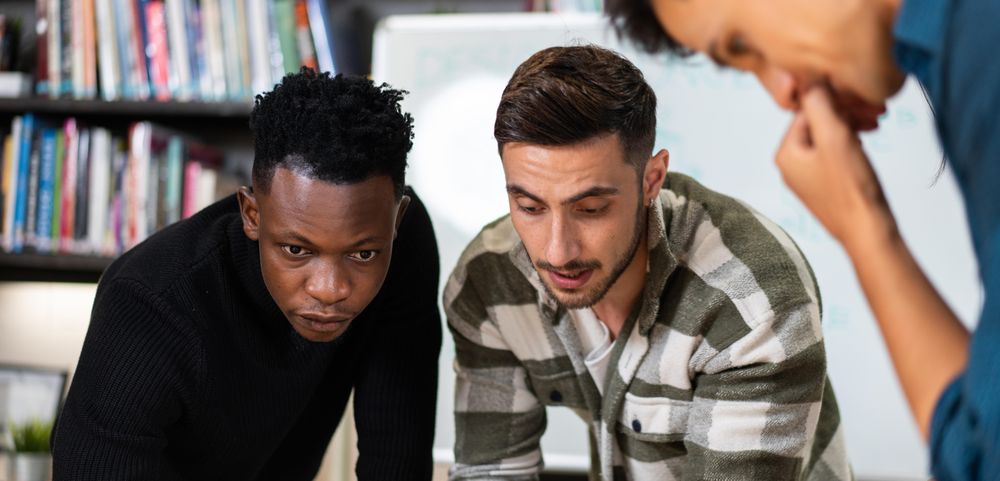 Multi-ethnic colleagues leaning over desk working on project