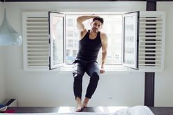Young happy man sitting on window