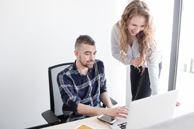 Cheerful colleagues working on laptop together