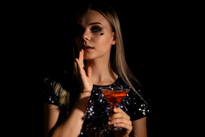 A woman at a party in the style of Halloween with a cocktail in her hands