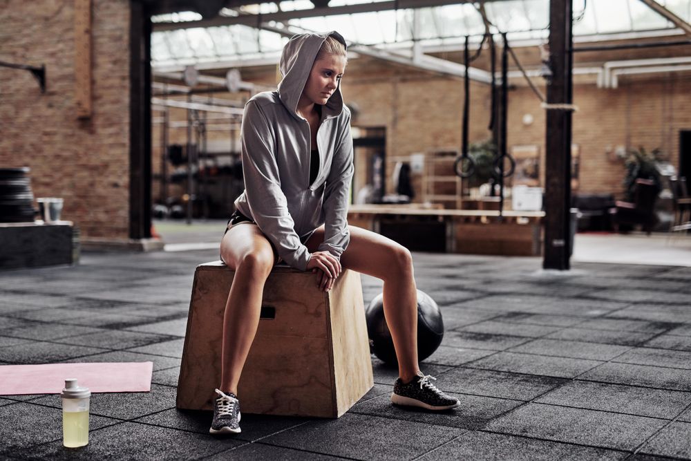 Woman sitting on box in gym with medicine ball