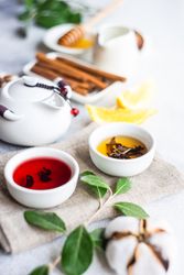 Two delicate cups of tea with tea pot in background