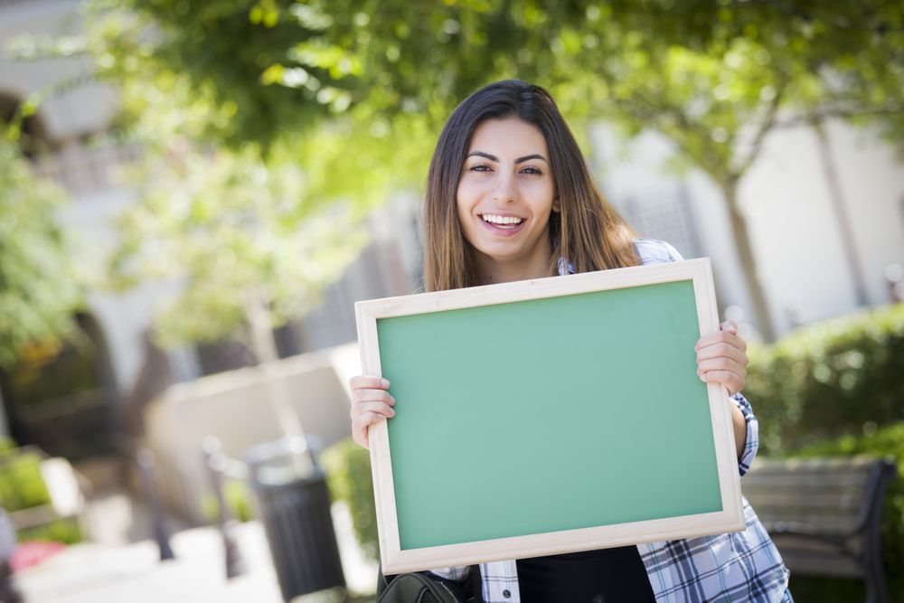 Happy Female Student Holding Blank Chalkboard