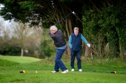 Man swinging club on golf course