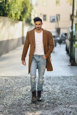 Man in smart winter jacket and jeans walking on street