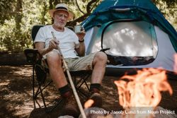 Mature man sitting relaxed near campfire and with a cup of coffee 4NKkDb