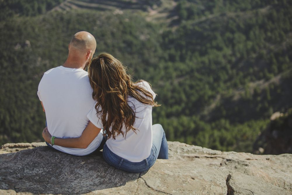 Happy couple sitting at mountain cliff