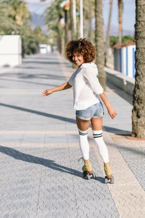 Woman on roller skates looking back and smiling at camera, vertical
