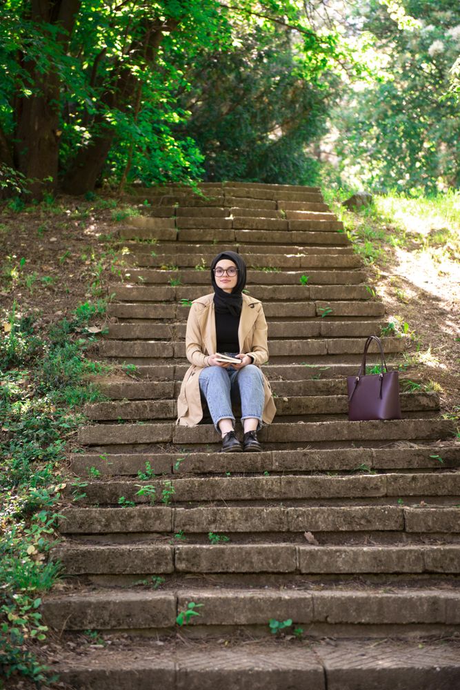 Woman sitting on outdoor stairs looking up from book