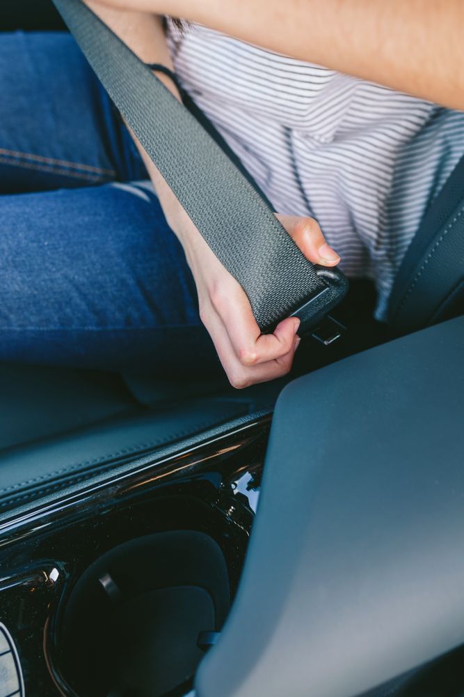 Young woman's hand putting on seatbelt