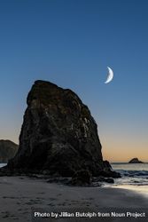 Crescent moon above quiet beach at dusk, vertical composition 4j9av5