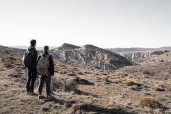 Two young male friends are watching a limestone formation in the distance during a hike