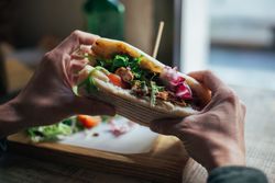 Hands holding loaded sandwich in cafe