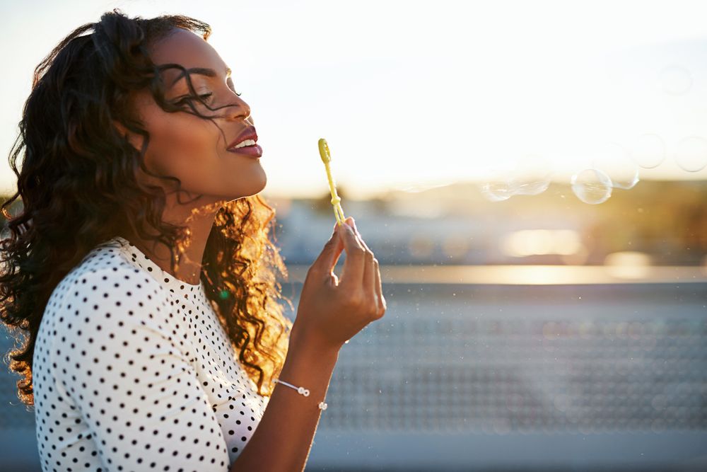 Side view of a Black woman blowing bubbles