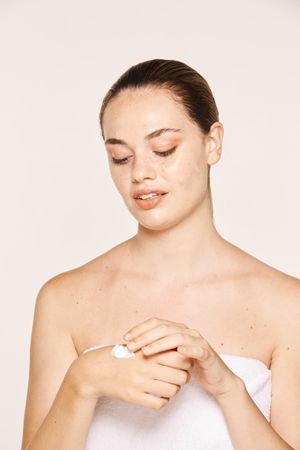 Delighted female applying recovery cream on hands