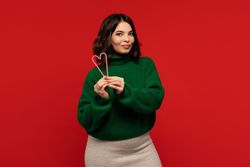 Woman holding two candy canes forming heart shape