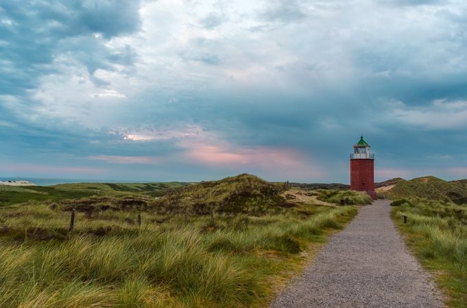 Landscape with a footpath through marram grass towards lighthouse on Sylt island, Germany