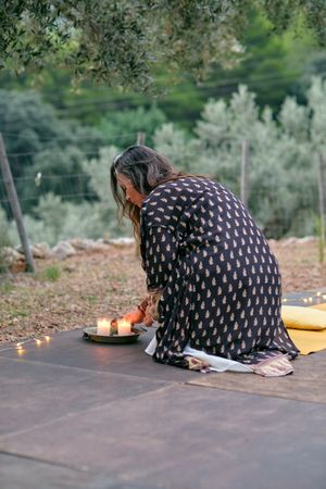 Woman lighting aromatic candles placed on mat preparing for meditation
