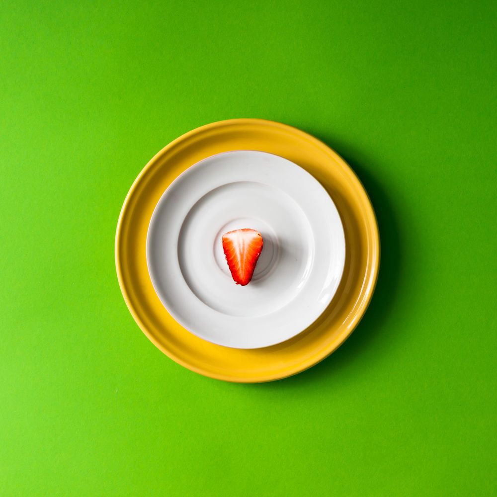 Strawberry half on plate setup on green background