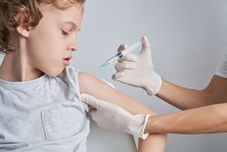Faceless nurse injecting kid with syringe
