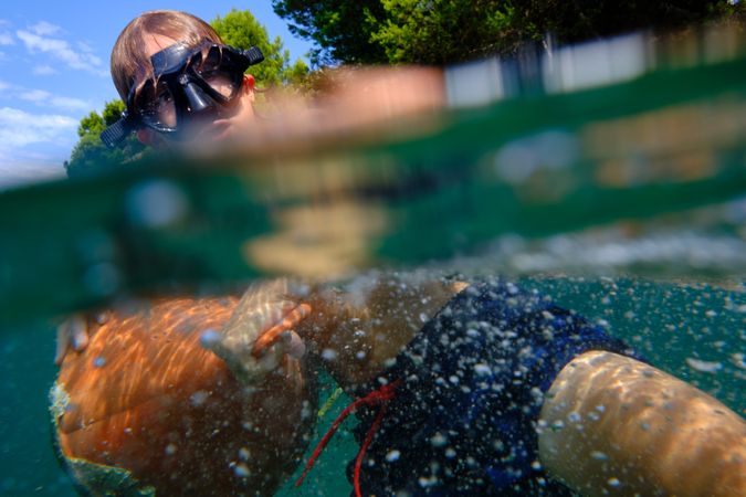 Boy swimming and holding onto buoy