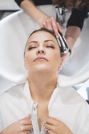 Stylist washing hairs to young woman