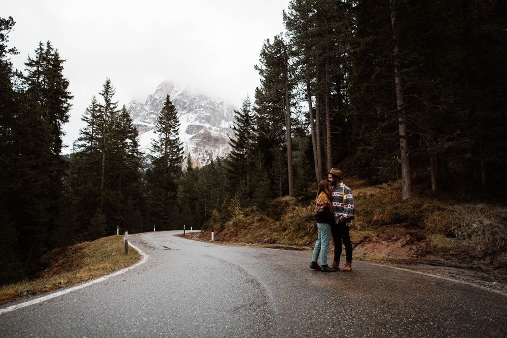 Casual resting couple standing in an embrace on route amid forest