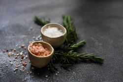 Close up salt bowls and rosemary on kitchen counter with copy space