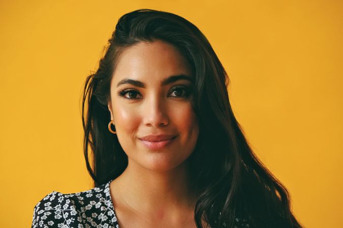 Smiling Hispanic woman wearing dress in yellow room, close up