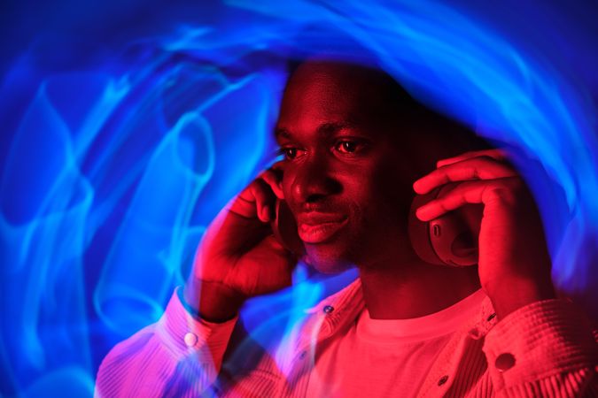 Smiling Black man in headphones in neon illumination