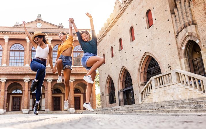 Three happy women dancing in Italian square