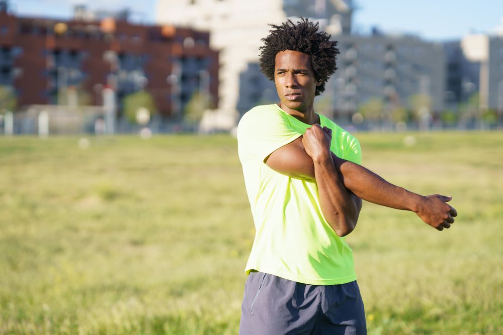 Man stretching arm in park outside