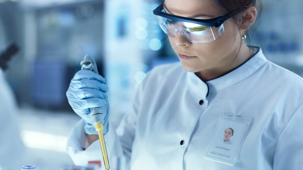 Female Research Scientist Uses Micropipette Filling Test Tubes in a Big Modern Laboratory.