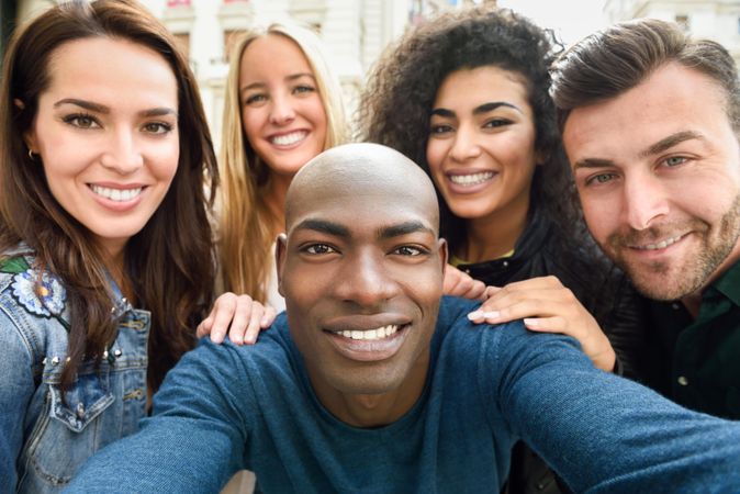 Multi-ethnic group of friends smiling at camera taking selfie