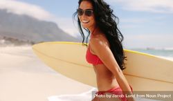 Smiling young woman with surfboard on beach 48anqb