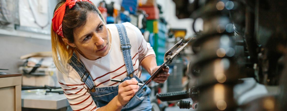 Mechanic woman filling out motorcycle documentation on garage