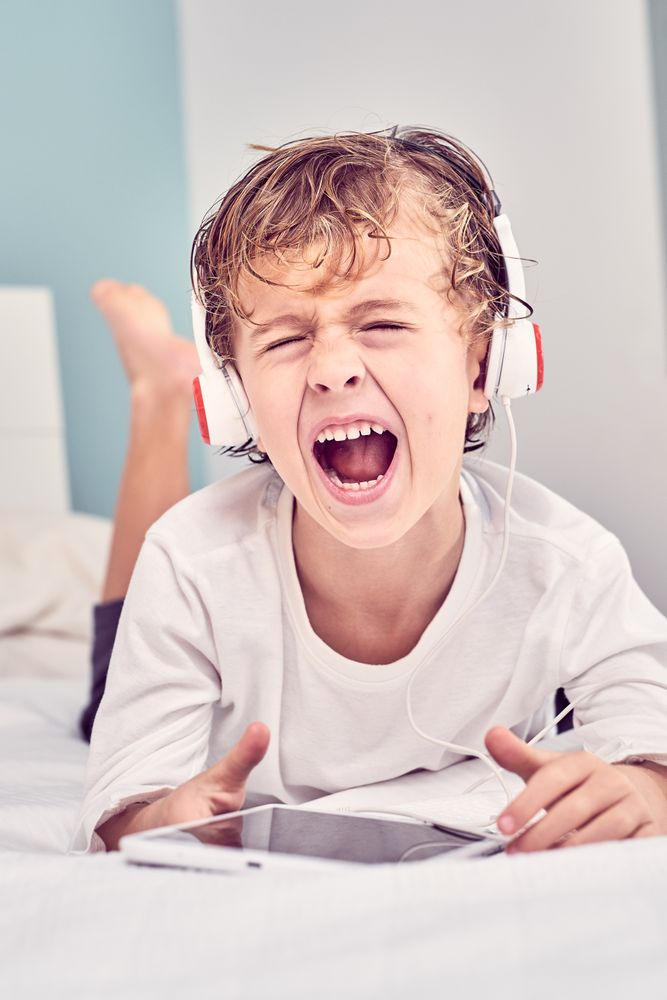 Boy screaming loud while listening to music from tablet