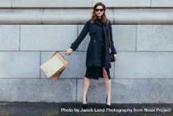 Stylish woman against wall with shopping bags 48BgJ7