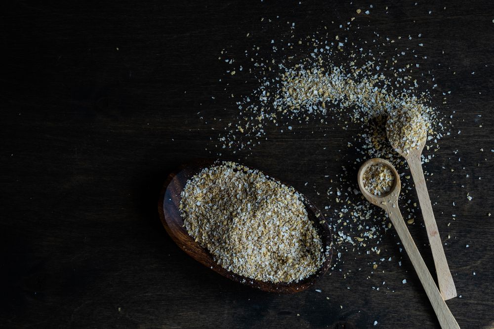 Ground oats with two wooden spoons on counter