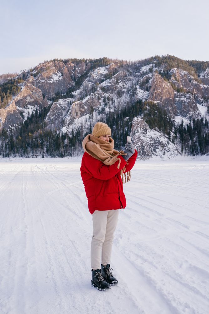 Woman taking picture of snowy mountains with smartphone