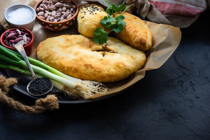 Traditional georgian pies with beans, chicken and eggs with green onion on dark wooden background