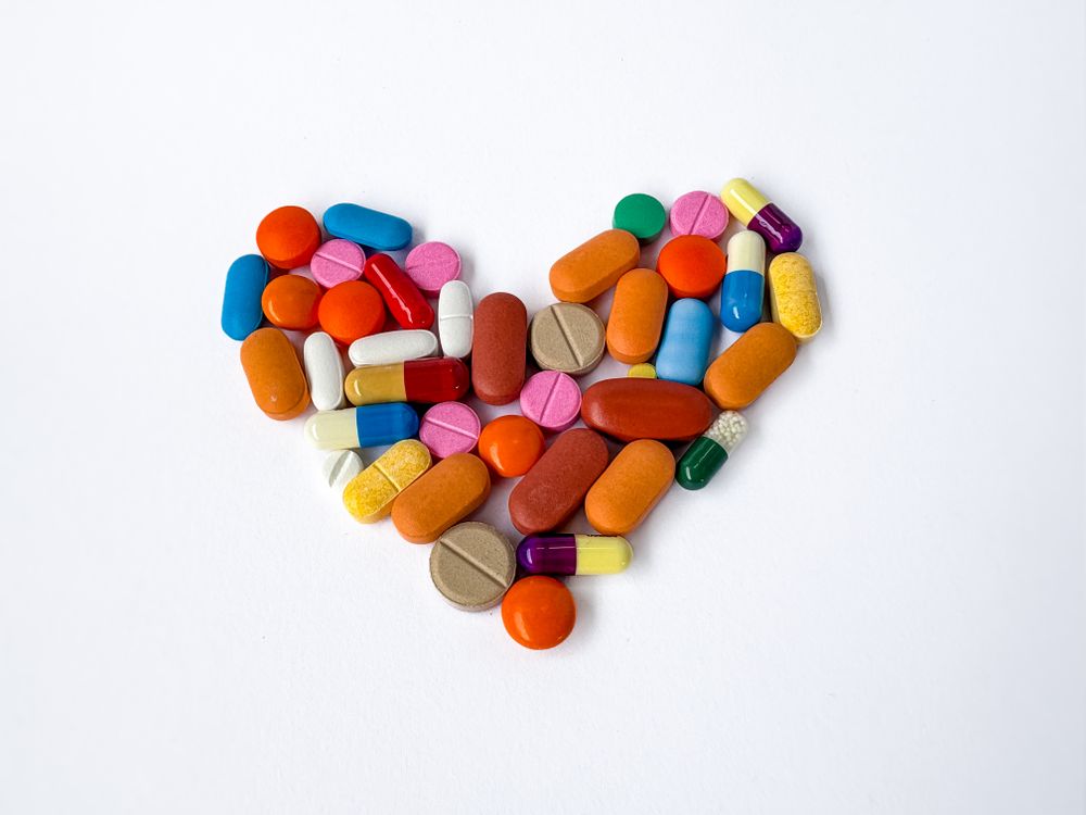 Colorful Pills and Capsules Forming Heart Shape on Paper Background
