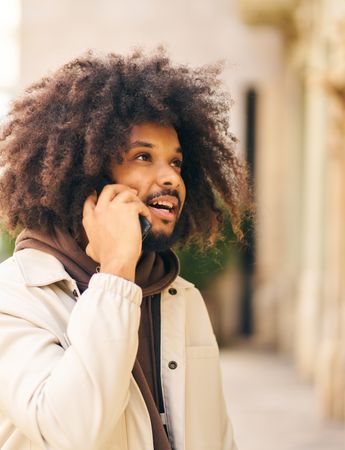 Young man with curly afro hair on the street talking on the cell phone