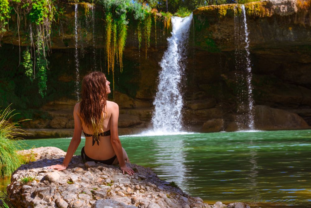 Young female relaxing near waterfall
