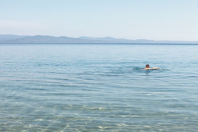 Man swimming in clear water in sunlight
