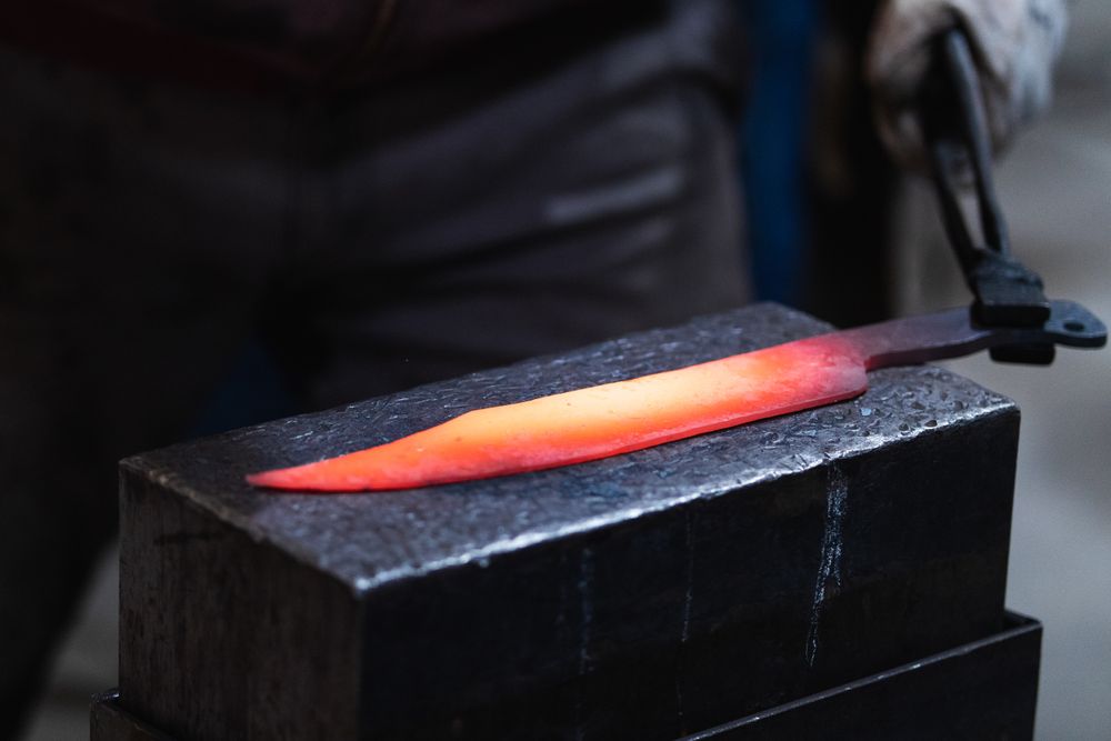 Master forging hot iron on anvil