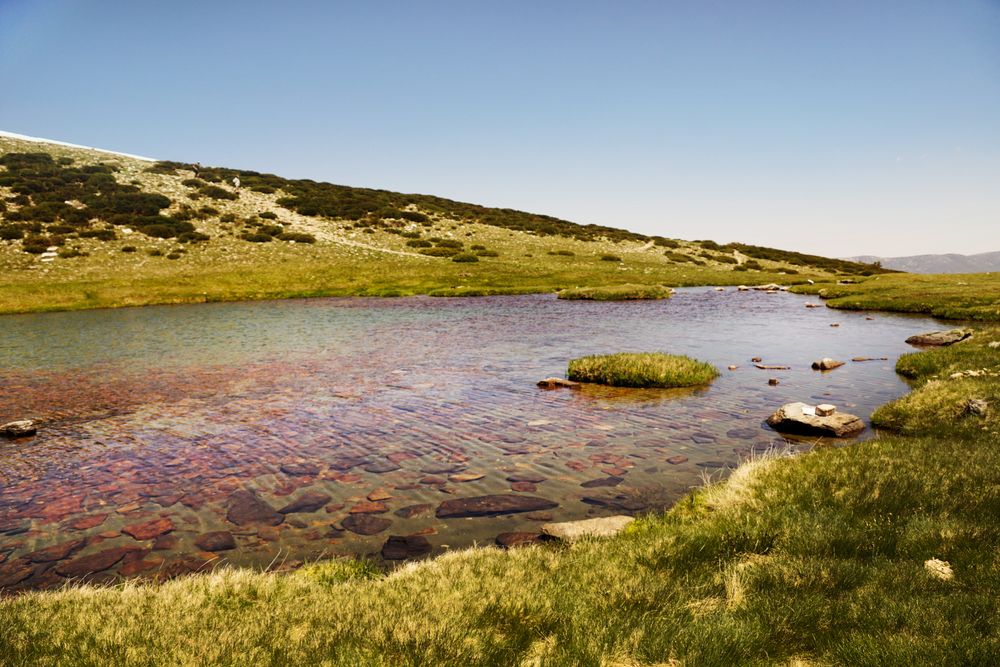 Clear lake at bottom of rocky mountain